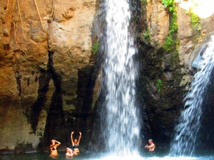 Visitors swimming in a lagoon under a waterfall